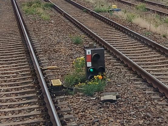 ein Hl-Zwergsignal zwischen zwei Gleisen, das ein grünes Licht über einem gelben Licht zeigt